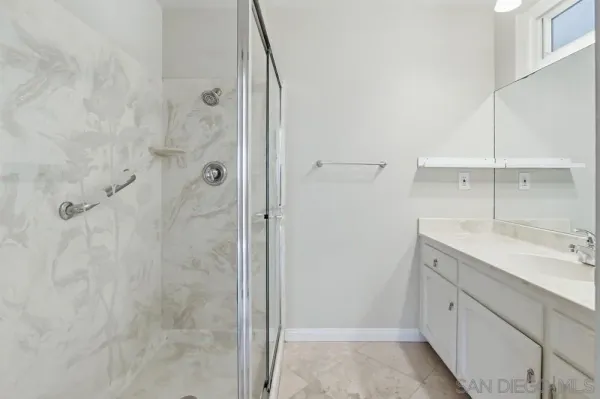 a spacious bathroom with a granite countertop sink a shower and a mirror