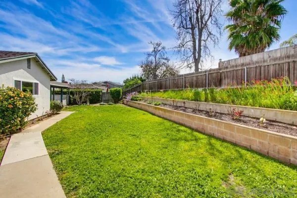 a view of a white house with table and chairs under an umbrella