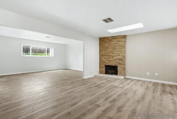 a view of empty room with wooden floor and fireplace