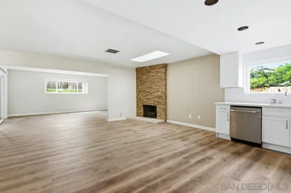 a view of an empty room with a kitchen and a window