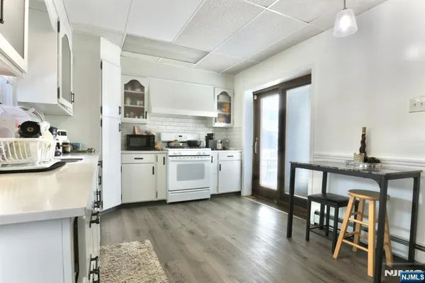 a kitchen with stainless steel appliances kitchen island wooden floors and white cabinets