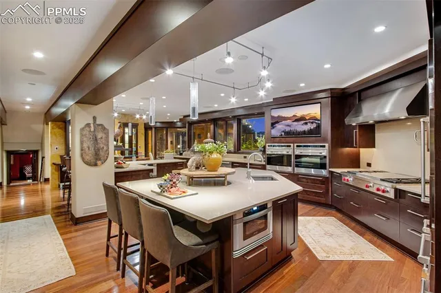 a kitchen with stainless steel appliances granite countertop a stove a sink dishwasher and a dining table with wooden floor