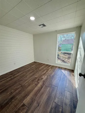 an empty room with wooden floor cabinet and windows