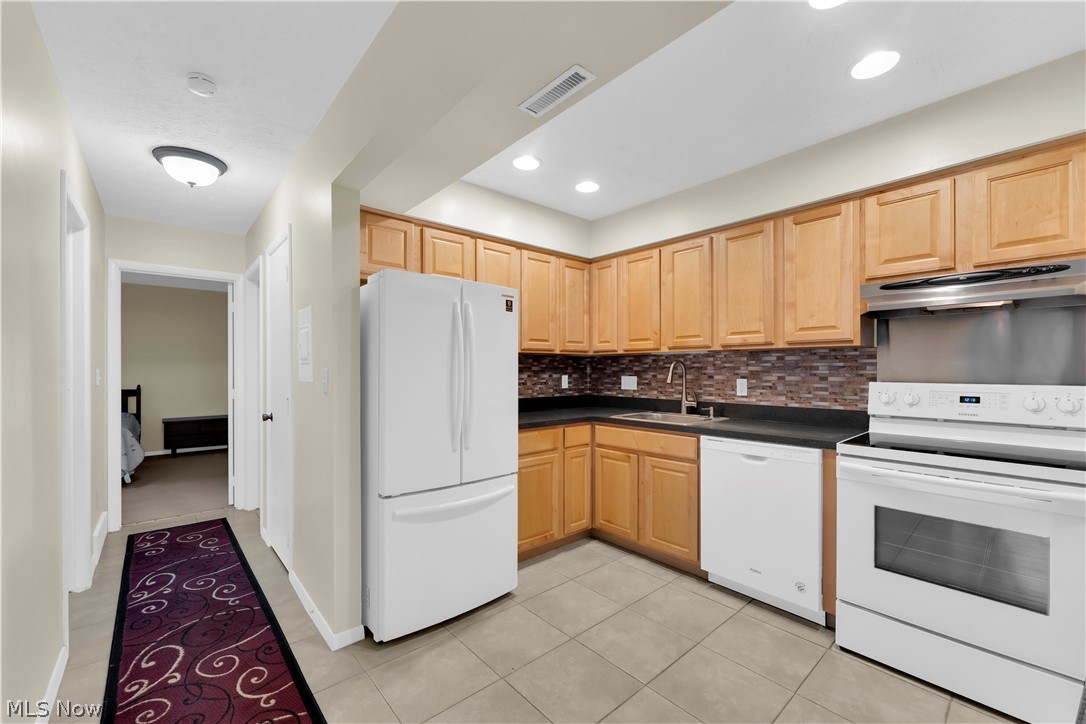 985 Canyon View Road, Unit 108D Northfield, OH 44067 - Photo 7 of 18 Kitchen with white appliances, light wood finish cabinets, backsplash, dark countertops, and light tile patterned floors