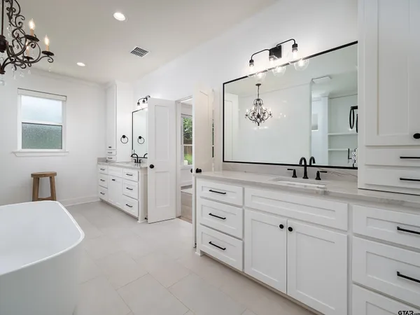 a spacious bathroom with double vanity sink a mirror and a bathtub