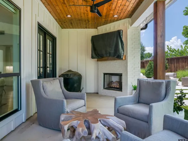 a outdoor living space with furniture a flat screen tv and a fireplace
