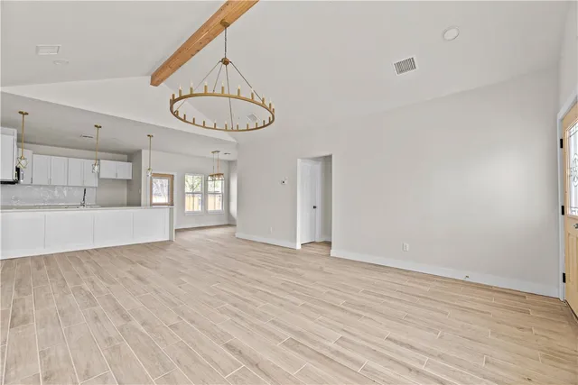 a view of an empty room with a window and kitchen view