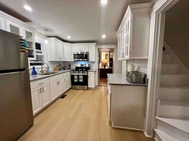 a kitchen with refrigerator a stove top oven a sink and cabinets