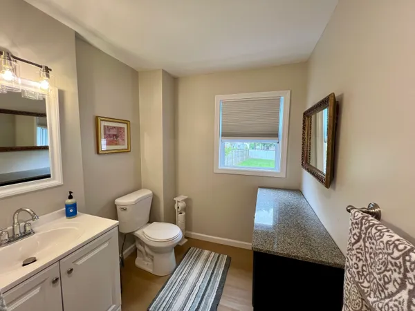 a bathroom with a granite countertop sink toilet and mirror