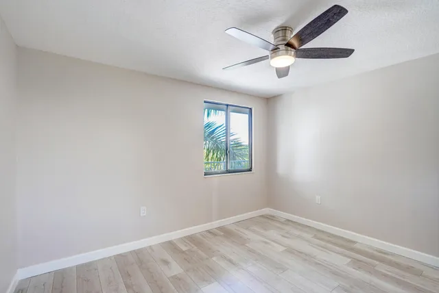 an empty room with window and ceiling fan