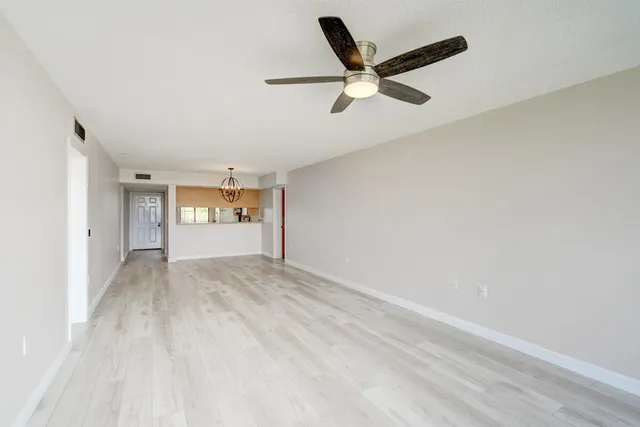 a view of a livingroom with a ceiling fan & windows