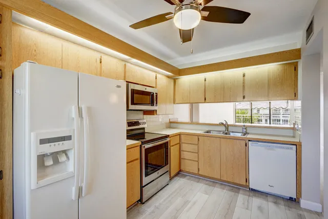 a kitchen with stainless steel appliances a refrigerator a sink and white cabinets