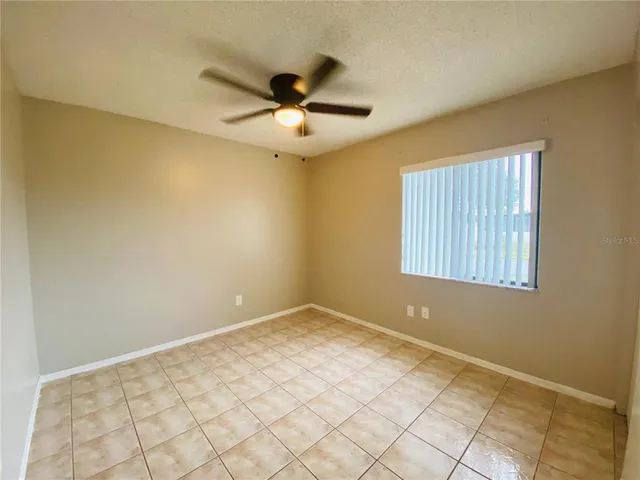 an empty room with windows and fan