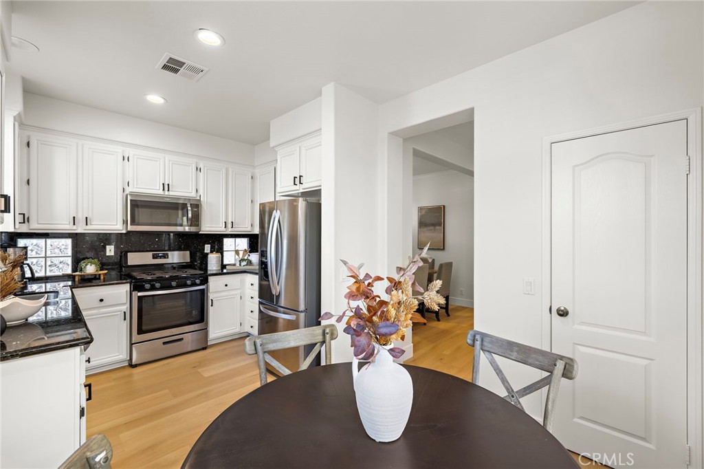 9 Paverstone Lane Ladera Ranch, CA 92694 - Photo 12 of 51 a kitchen with stainless steel appliances kitchen island granite countertop a refrigerator a stove top oven and a dining table with wooden floor