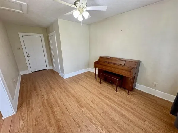 an empty room with wooden floor fan and windows