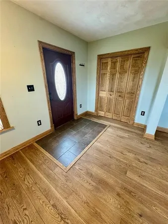 a view of an empty room with wooden floor and window