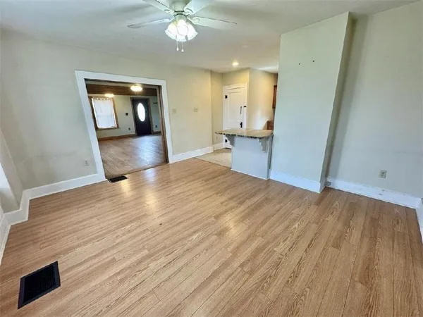 a view of an empty room with wooden floor and a window