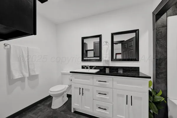 a bathroom with a granite countertop toilet sink and mirror