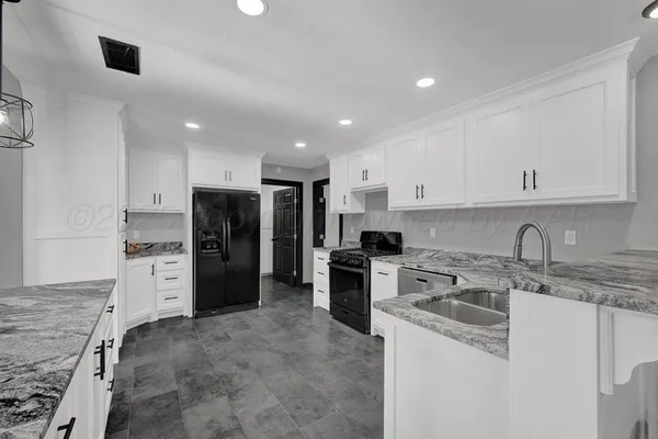 a kitchen that has a refrigerator a sink a stove and cabinets