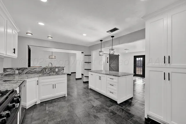 a kitchen with granite countertop a sink and a stove top oven