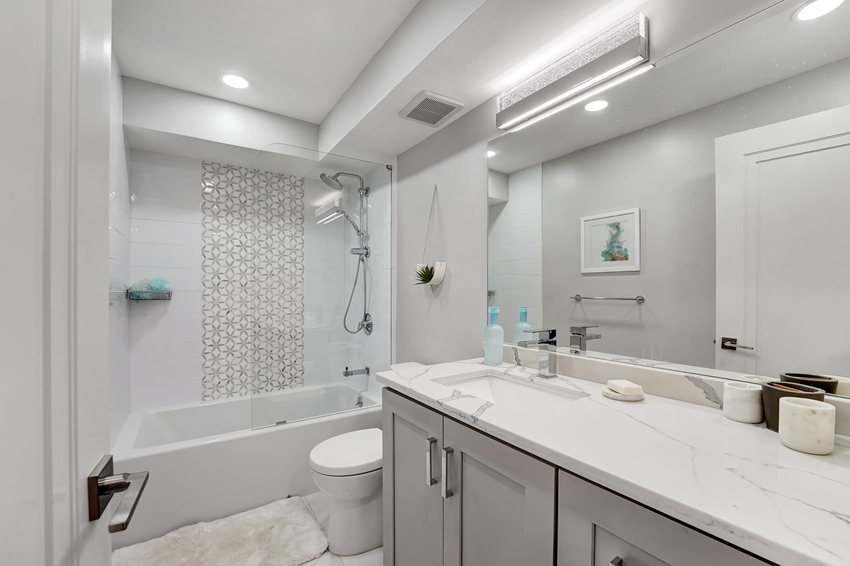 2175 South Ocean Boulevard, Unit 304 Delray Beach, FL 33483 - Photo 21 of 28 a bathroom with a granite countertop sink a toilet a mirror a bathtub and shower