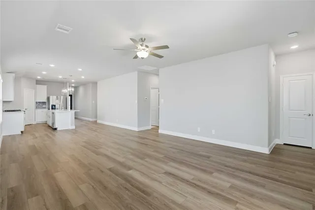 a view of empty room with wooden floor and ceiling fan