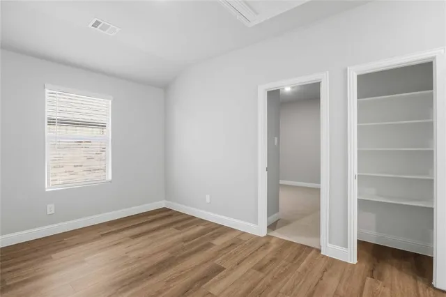 an empty room with wooden floor closet and windows