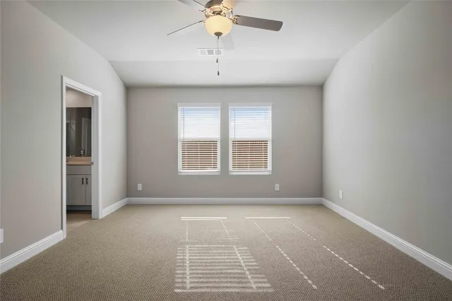 an empty room with chandelier fan and windows