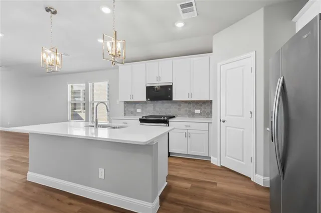 a kitchen with kitchen island granite countertop a sink cabinets and stainless steel appliances
