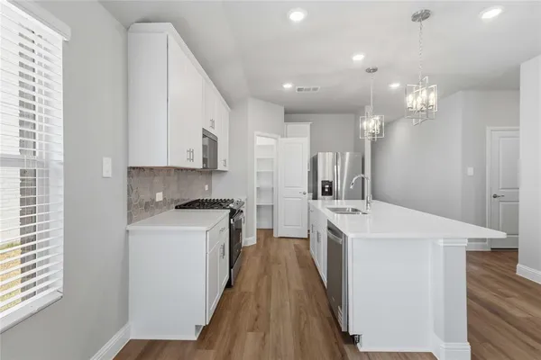 a kitchen with kitchen island a sink a stove a refrigerator cabinets and a window