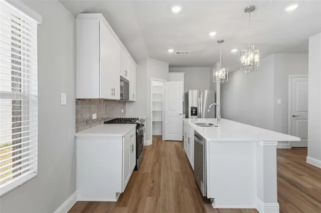 a kitchen with kitchen island a sink a stove a refrigerator cabinets and a window