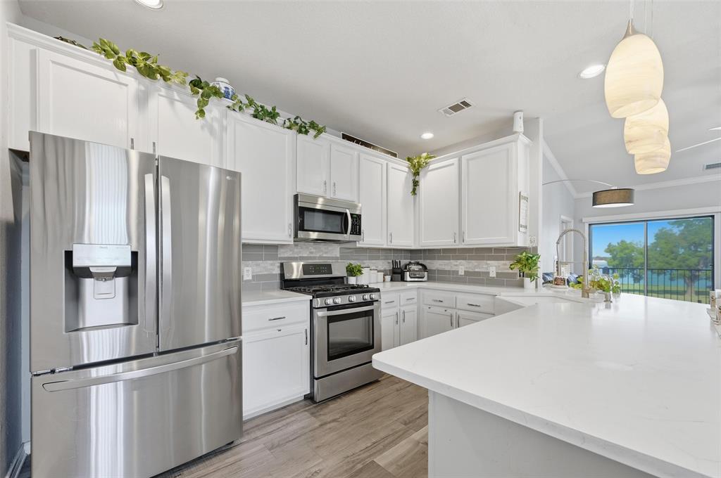 1904 Signal Ridge Place Rockwall, TX 75032 - Photo 10 of 23 Kitchen featuring appliances with stainless steel finishes, white cabinets, tasteful backsplash, decorative light fixtures, and light wood-style floors