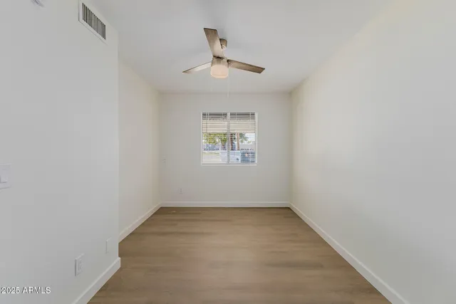 an empty room with a window and ceiling fan