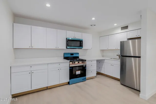 a kitchen with white cabinets and stainless steel appliances