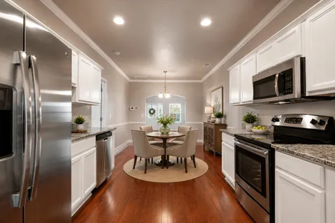 a kitchen with stainless steel appliances granite countertop a refrigerator a stove a sink dishwasher a dining table and chairs with wooden floor