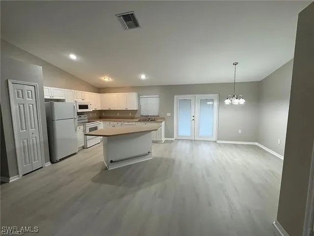 a large kitchen with a refrigerator a stove top oven a counter space and wooden floor