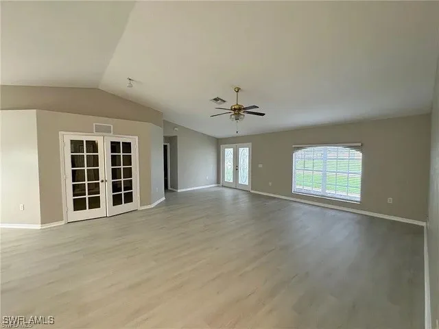a view of an empty room with a window and chandelier fan