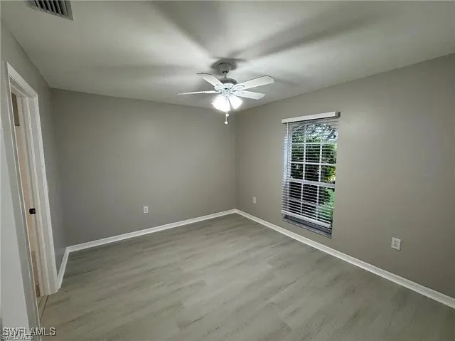 an empty room with windows and fan