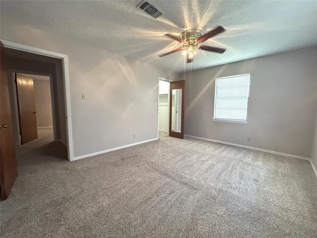 an empty room with windows and fan