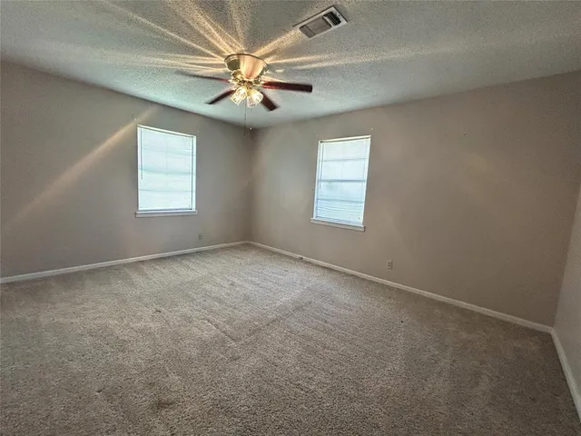 an empty room with windows and fan