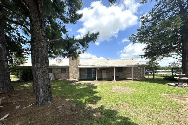 a view of house with a yard in the background