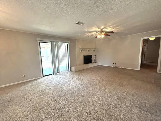 an empty room with chandelier fan and windows