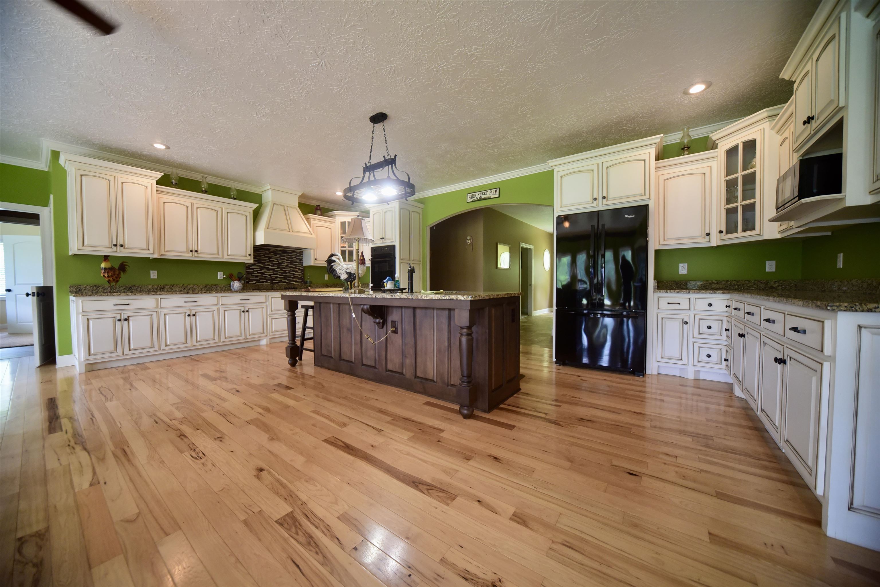 1359 Macks Grove Road Palmersville, TN 38241 - Photo 11 of 40 Kitchen featuring black appliances, custom exhaust hood, a breakfast bar, arched walkways, and light wood-type flooring