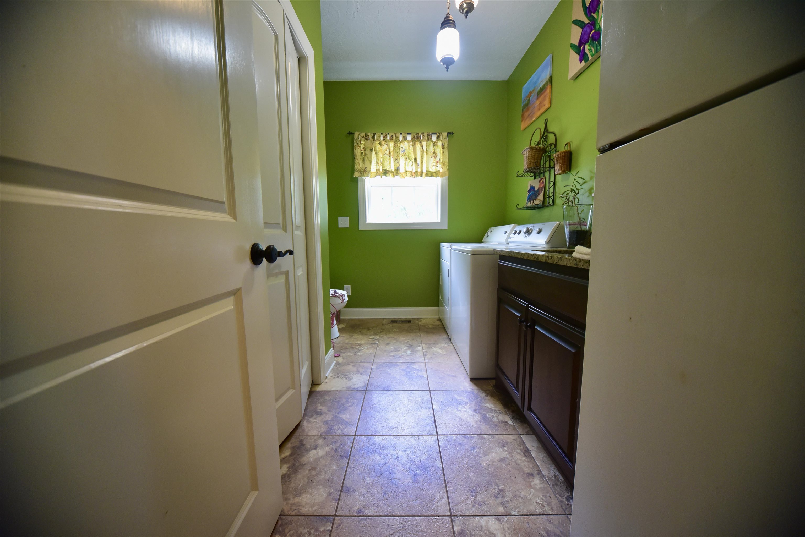 1359 Macks Grove Road Palmersville, TN 38241 - Photo 23 of 40 Laundry area with washer and clothes dryer, cabinet space, light tile patterned floors, and baseboards