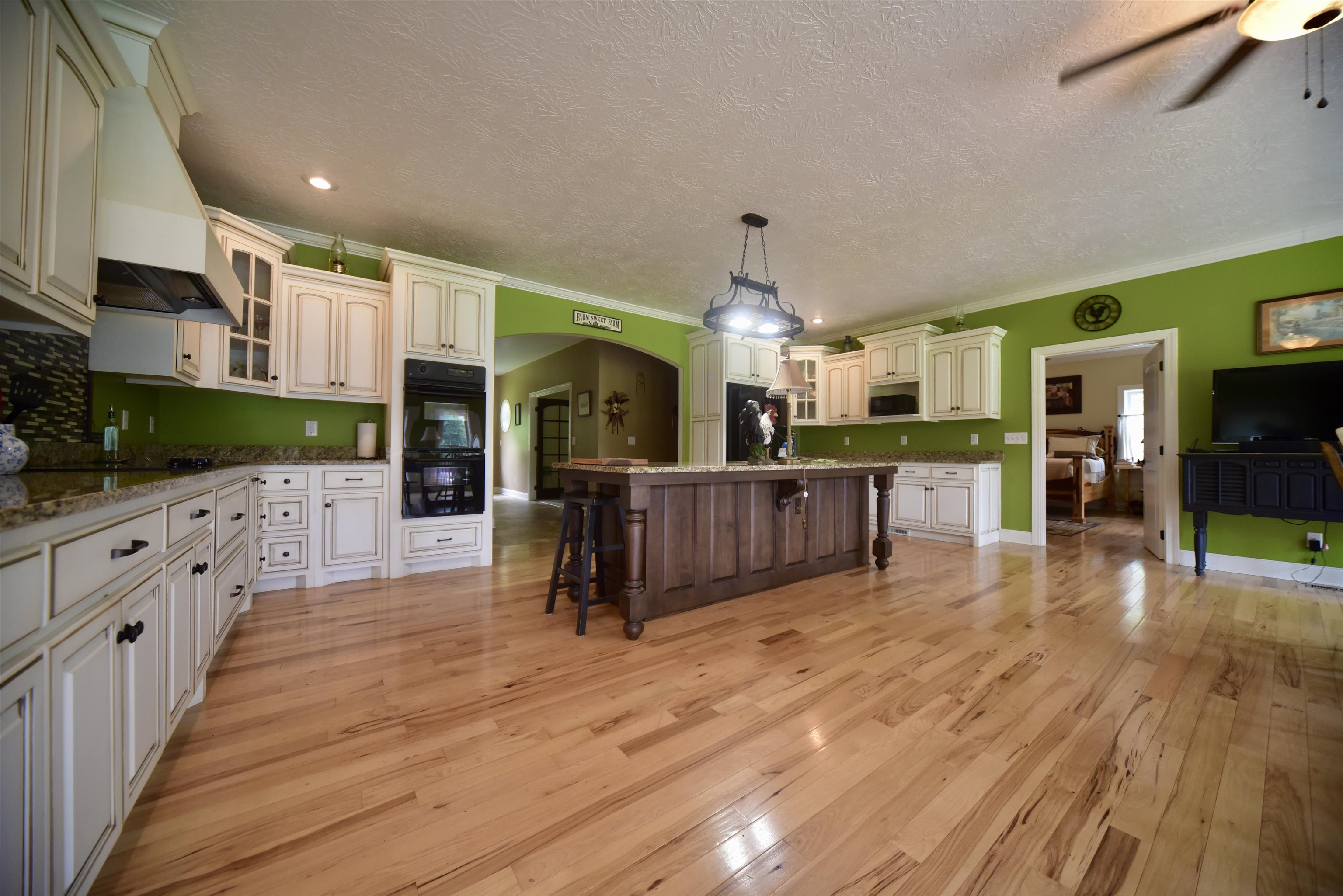 1359 Macks Grove Road Palmersville, TN 38241 - Photo 10 of 40 Kitchen featuring black appliances, a kitchen breakfast bar, arched walkways, light wood finished floors, and a textured ceiling