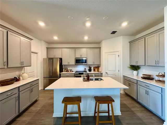 a kitchen with a sink a refrigerator and chairs