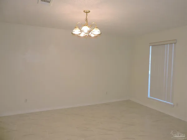 an empty room with windows fireplace and fan