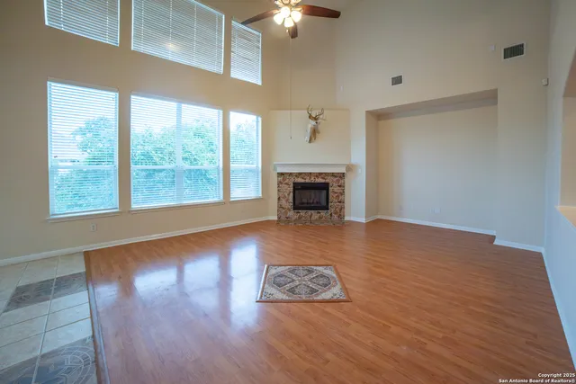 an empty room with wooden floor fireplace and windows
