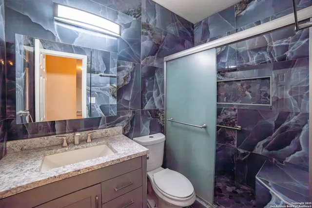 a bathroom with a granite countertop sink toilet and shower