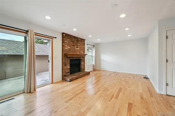 an empty room with wooden floor a fireplace and windows